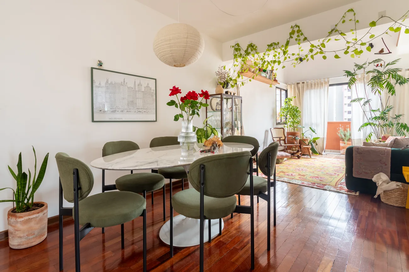 Sala de jantar com mesa de mármore, cadeiras verdes e plantas integradas ao ambiente